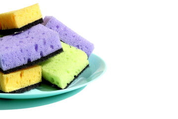 On a white background, there are many rectangular dishwashing sponges lying on a plate.	