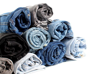 Denim trousers are folded into rolls on a white background.
