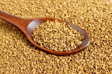 A wooden spoon lies on a background of instant coffee.	