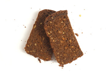 Pieces of black rye bread with sunflower seeds lie on a white background.	