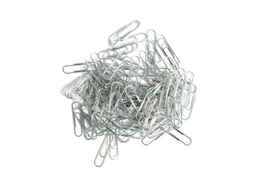 A pile of iron paper clips lie on a white background.	