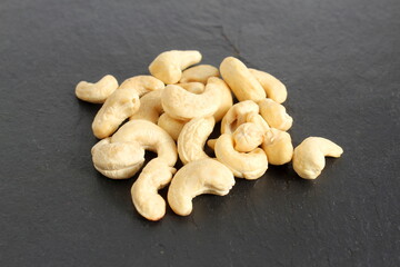 There is a small pile of cashew nuts on a black background.