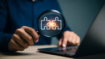 Magnifying Glass Focusing on Two Interlocking Puzzle Pieces on Laptop Solution Concept