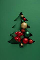 Elegant cutout Christmas tree reveals colorful ornaments and a red ribbon gift, set against a deep...