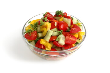 There is a transparent plate with a salad of fresh vegetables on a white background.	