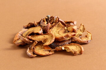 There is a small pile of dried apple pieces on a brown background.