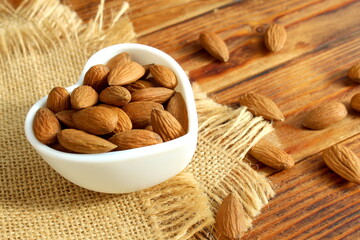 There is a bowl of almonds on the wooden table.	