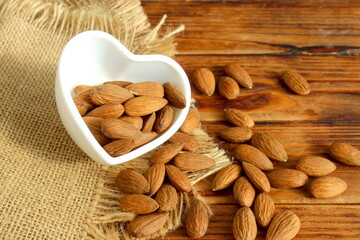 There is a bowl of almonds on the wooden table.