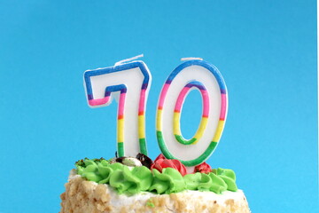 On a blue background there is a festive cake with an anniversary candle with the number