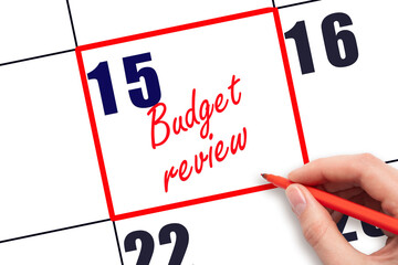 15 th day of the month.  Hand writing Budget review reminder and drawing red frame on calendar with...