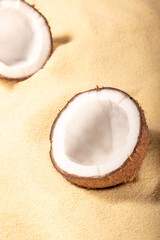 Minimal concept with Cracked coconuts on sandy background.