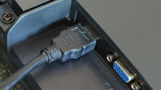 Hand plug, insert, input or connect a HDMI cable cord into a monitor device port or socket hole. Close up macro top view. High definition video and audio multimedia technology concept.