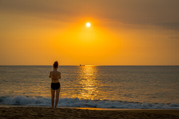 Fototapeta premium Femme regardant le couché de soleil sur l'océan Atlantique depuis la plage du Métro à Tarnos en France