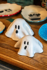 halloween ceramic decorations, decorative ghost ceramic pieces displayed on rustic wooden shelves