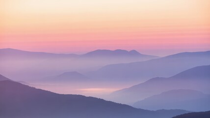 Fototapeta premium Layered mountain ranges fade into soft pink and orange sky at dawn landscape nature