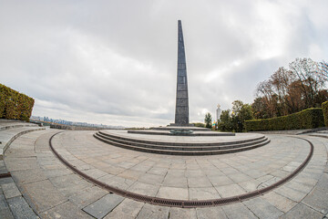 Overcast Kiev panorama featuring a central, tall rectangular stone monument on a circular paved...