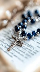 Close-up of rosary beads and crucifix on open bible page, All Saints' Day