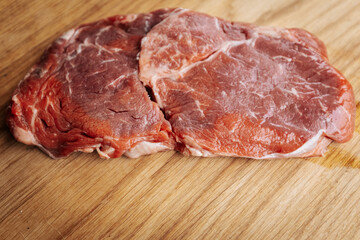 Close-up of raw, marbled meat cuts, freshly sliced and ready for cooking or grilling, showcasing texture and quality in a culinary preparation setting.