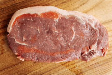 Close-up of raw, marbled meat cuts, freshly sliced and ready for cooking or grilling, showcasing...