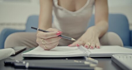 Close-up on a girls hands as she meticulously draws or writes in a spiral notebook using a pencil. The video features the authentic, relaxing sounds of her creative process, perfect for focus and calm - Powered by Adobe