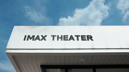 IMAX Theater word sign prominently displayed on the large entertainment complex facade beneath a clear blue sky, signifying a cinema featuring the specialized, high-resolution IMAX film format