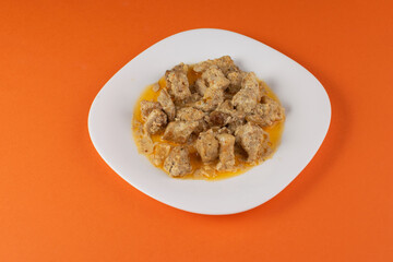 Savory Stew on White Plate Against Vibrant Orange Background - Homestyle Comfort Food