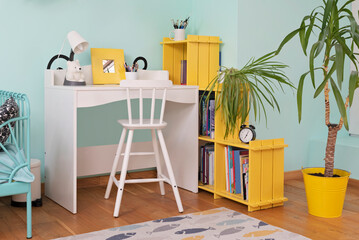 Child room in modern design. White desk with chair and yellow decor and furniture in cozy interior for children. Carpet on wooden floor. Scandinavian style.