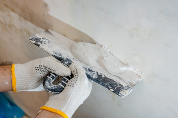 Detailed process shot of a professional plasterer applying material with a trowel, a key step in...