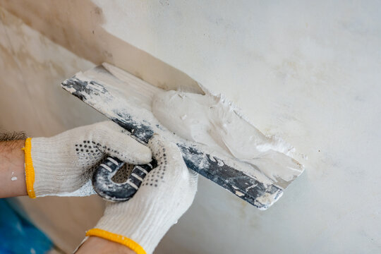 Detailed process shot of a professional plasterer applying material with a trowel, a key step in modern construction and building.