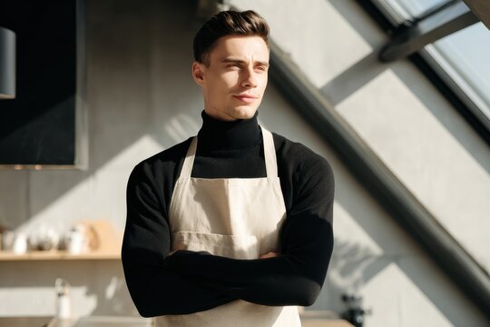 Confident Chef Posing: A handsome chef stands with arms crossed, exuding confidence and culinary expertise within a modern kitchen setting. The image is bathed in natural light.