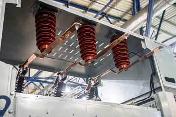 Close-up of high-voltage electrical switchgear components, featuring robust red insulators and...
