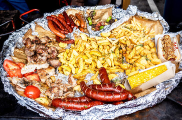 Frying pan with fried potatoes, sausages, meat, vegetables and pepper. Street food and outdoor cooking