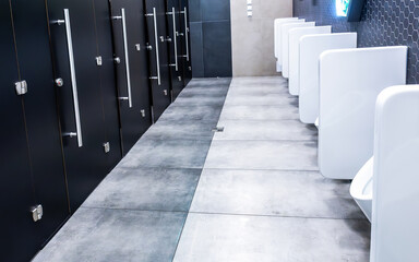 Interior of public bathroom with cabins and ceramic urinals