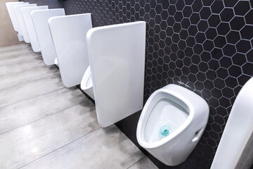 Ceramic urinals in a row in public toilet