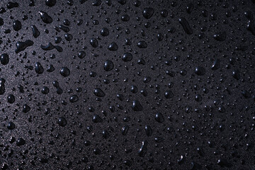 Studio macro of fine droplets on black water repellent texture. Clean premium background for waterproof products, electronics and outdoor branding.
