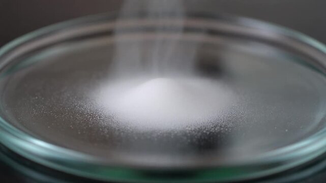 A small amount of ammonium chloride sublimating into white vapor on a glass plate.
