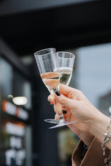 Close-up of woman holding two champagne glasses during outdoor celebration or toast moment