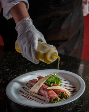 cocinera aderezando un carpaccio de res 