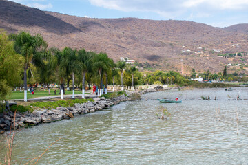 Walking path by Lake Chapala in Jocotepec, Jalisco, with palm trees and rocky shore