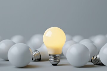 Glowing light bulb amidst unlit bulbs on gray background