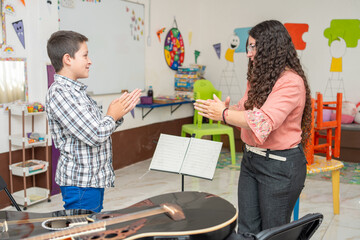 Guitar teacher and young student standing and clapping hands to learn rhythm and timing during a private music lesson. Concept of musical training, coordination, and interactive learning