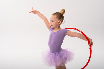 Little ballerina with cochlear implant performing pose with red hoop. Inclusion, hearing awareness,...