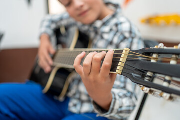 Close-up of a boy’s hand playing acoustic guitar during a music lesson. Focus on strings and technique, showing practice and concentration. Learning instrument, childhood education concept