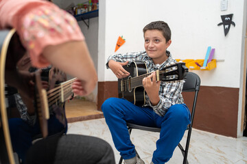 young boy playing acoustic guitar during his music lesson. Focused child musician learning instrument technique. Music education, talent, artistic growth