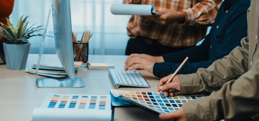 A diverse team works together in a modern office environment, selecting color palettes and designs while sharing ideas and resources for their creative project. SACTR