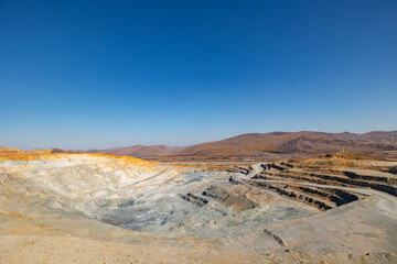 Panorama of open pit mine extracting gold, iron ore with heavy trucks, excavators.