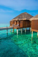 Tranquil closeup calm sea water waves with palm trees. Beautiful Cabins. Tropical island beach landscape exotic shore coast. Summer vacation, holiday amazing nature. Relax paradise, Maldives.