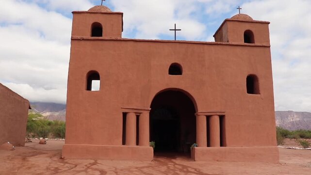 Frontal and symmetrical view of the historic adobe church of Nuestra Senora de Andacollo in La Falda, Catamarca. Rural religious landmark.