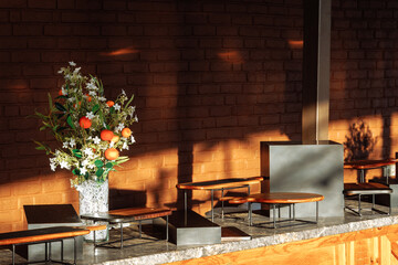 Modern catering display with floral arrangement and tiered stands on marble bar against brick wall