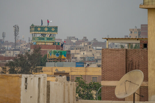 Cairo, Egypt - People standing on top of a traditional wooden pigeon tower on a residential rooftop